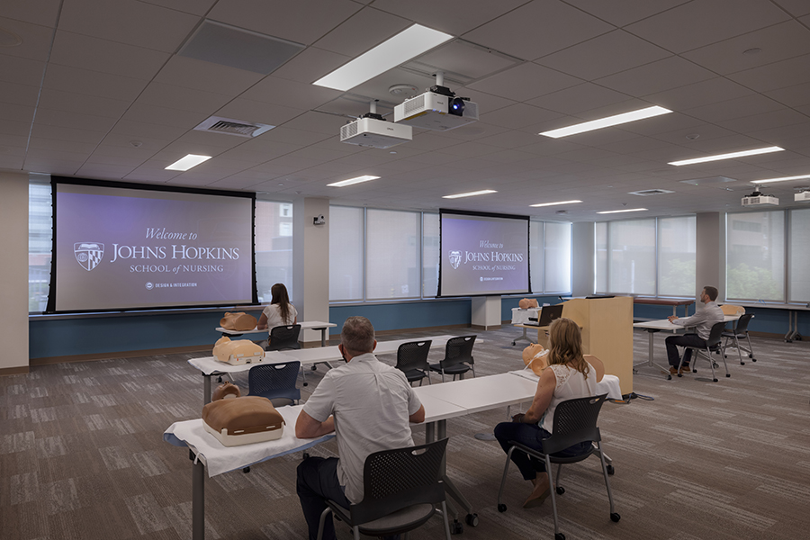 Students of Johns Hopkins School of Nursing in a classroom with projector and projection screens